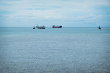 Beautiful wave with blue sky over the horizon on the beach background. Tropical colorful coast from the landscape sea. Jetty to the ocean with fishing boat. The holiday summer vacation concept.