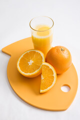 orange and orange juice on fish shaped cutting board