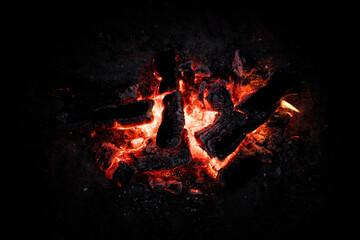Red hot coals glowing on a dying campfire pit. Orange glow from embers on a fire at night background