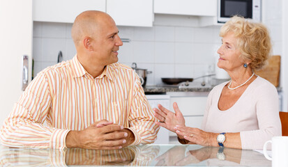 Man and his elderly mother having conversation at kitchen table
