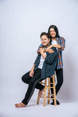 Two women lovers grab another shoulder and sit in a chair.