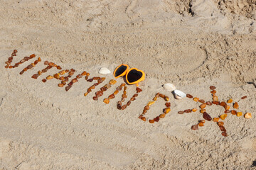 Obraz premium Inscription vitamin D with shape of sun and sunglasses on sand at beach. Prevention of vitamin D deficiency