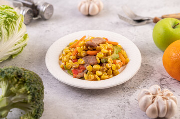 Stir the corn and carrots, put the pork on the plate on the wooden plate.