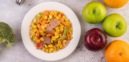 Stir the corn and carrots, put the pork on the plate on the wooden plate.