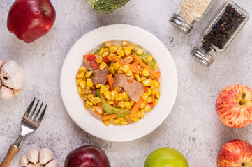 Stir the corn and carrots, put the pork on the plate on the wooden plate.