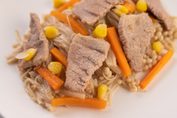 Stir the corn and carrots, put the pork on the plate on the wooden plate.