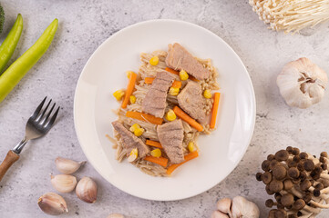 Stir the corn and carrots, put the pork on the plate on the wooden plate.