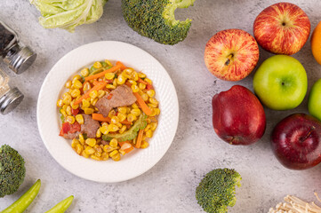 Stir the corn and carrots, put the pork on the plate on the wooden plate.