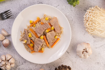 Stir the corn and carrots, put the pork on the plate on the wooden plate.