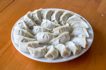 A plate of freshly wrapped raw dumplings, traditional Chinese food