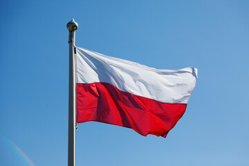 Fototapeta na wymiar Poland's red and white flag on blue summer sky