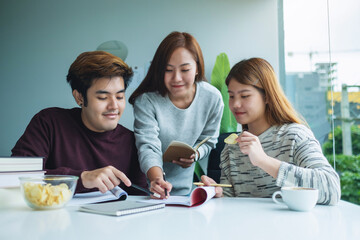 Group of young students tutoring and  catching up workbook with friends