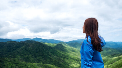 Naklejka premium Portrait image of female traveler looking at a beautiful green mountains view