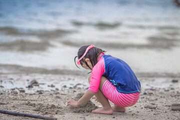 Close-up background view of an Asian girl, playing in the sea on the beach, with a parent or guardian supervising during the holidays, family getaways.