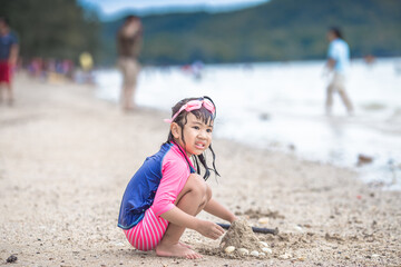 Close-up background view of an Asian girl, playing in the sea on the beach, with a parent or guardian supervising during the holidays, family getaways.