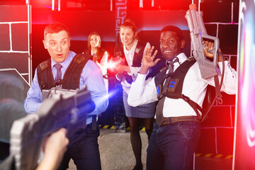 Group of smiling colleagues holding laser pistols playing laser tag game