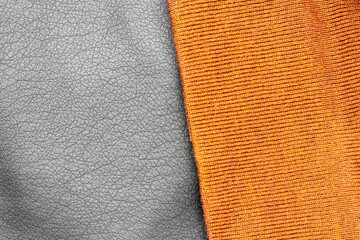 Close up of black vintage, stylish and fashion PU leather jacket texture and modern orange hat from polyester and acrylic fabric material with the textured surface, isolated, from above, background.