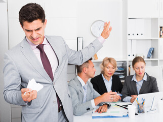 Businessman standing apart feeling angry to coworkers in office