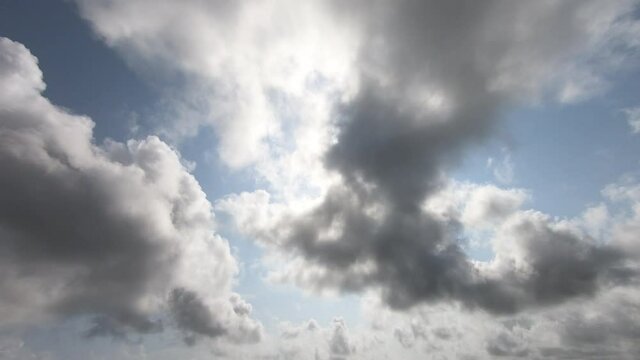 Amazing timelapse video of fast moving dense clouds, appearing and disappearing in ever changing pattern with clear blue sky and bright big sun in background. Concept of oncoming of rains, weather etc