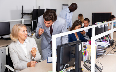 Outraged manager expressing dissatisfaction with work of frustrated mature woman in coworking space.