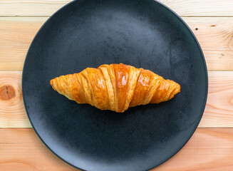 Croissants are placed in black plates that are placed on the wooden floor