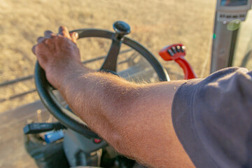 Tanned hand of the combine operator close-up on the steering wheel