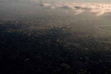 Fototapeta premium Bangkok city's bird eye view shot from a plane that flight in a morning with warming color of sunrise and some shade from clouds .photo may had some noise and partly blur