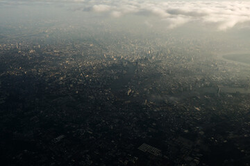 Bangkok city's bird eye view shot from a plane that flight in a morning with warming color of sunrise and some shade from clouds .photo may had some noise and partly blur