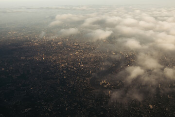 Bangkok city's bird eye view shot from a plane that flight in a morning with warming color of sunrise and some shade from clouds .photo may had some noise and partly blur