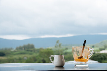 hot Thai's style milk tea in a cup with mountain view when a raining is coming from somewhere faraway