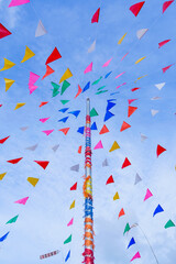 Fototapeta premium vivid color of Thai's style fancy party flag strips decoration on a fancy still pole with blue sky and white cloud in background