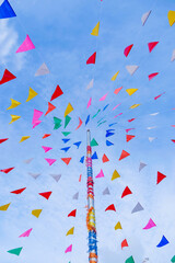 Fototapeta premium vivid color of Thai's style fancy party flag strips decoration on a fancy still pole with blue sky and white cloud in background