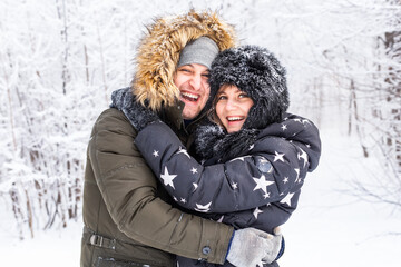 Obraz premium Young couple in love have fun in the snowy forest. Active winter holidays.