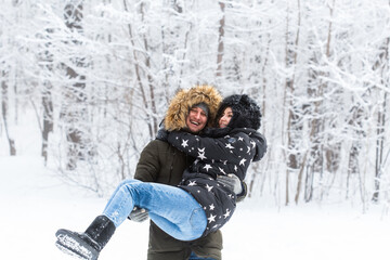 Fototapeta na wymiar Young couple in love have fun in the snowy forest. Active winter holidays.