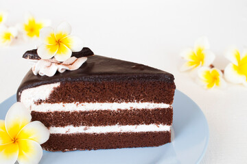 Fototapeta na wymiar dessert snack chocolate cake with flowers frangipani arrangement flat lay style on background wooden white