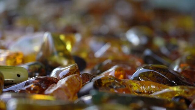 Handheld Shot with Rack Focus on Polished Scattered Pieces of Amber with Rich Orange Colour