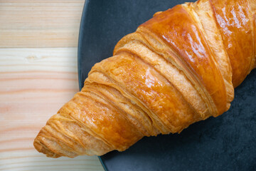 Croissants are placed in black plates that are placed on the wooden floor