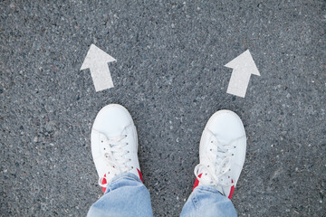 Sneakers on the asphalt with arrows.