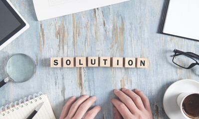 Solution word on wooden cubes with a business objects and human hands.