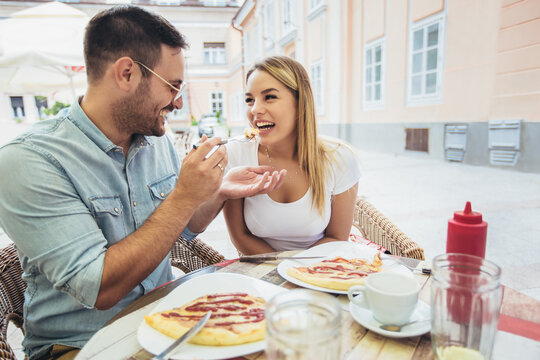 Photo of young couple enjoying in pizza, having fun together.