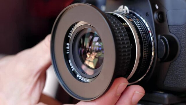 Male hand adjusts manual focus ring on a DSLR lens.  Close-up on lens rack-focusing.