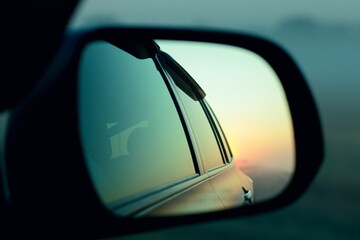 Side mirror of the car. Dawn on the highway.