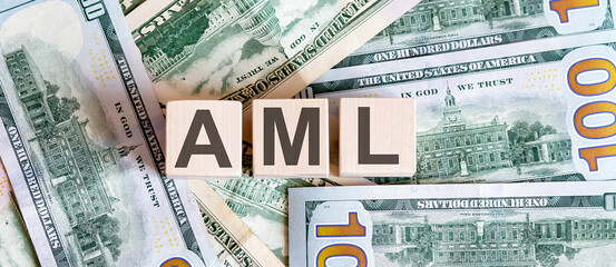 Concept words AML on wooden blocks on a beautiful background from dollar bills.