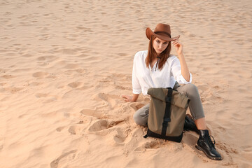 Beautiful fashionable young woman with backpack in desert