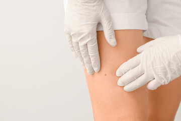 Dermatologist examining patient on grey background