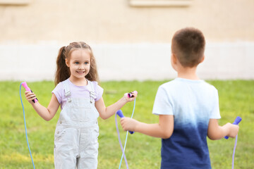 Cute little children jumping rope outdoors