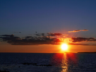 Sunset sky over ocean, Galway bay, Ireland, Warm orange and dark blue tones, Sun flare. Nobody.