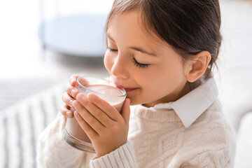 Little girl drinking tasty chocolate milk at home