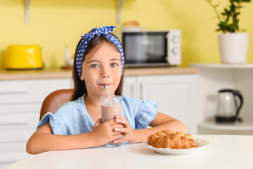 Little girl drinking tasty chocolate milk at home