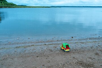 Obraz premium Children's toy car on the beach of a lake with blue water